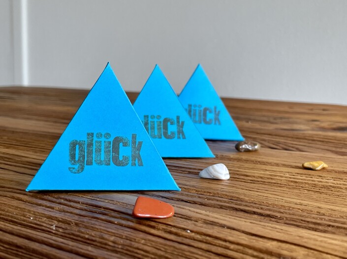 Drei kleine Papierpyramiden mit der Aufschrift „Glück“