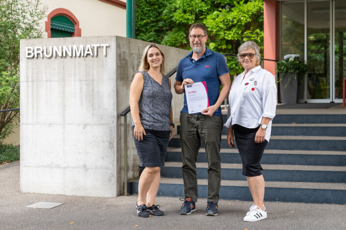 Jennifer Kiener, Andreas Meyer, Susanne Dörflinger stehen mit dem iPunkt Zertifikat in der Hand vor dem Eingang des Pflegezentrums Brunnmatt.